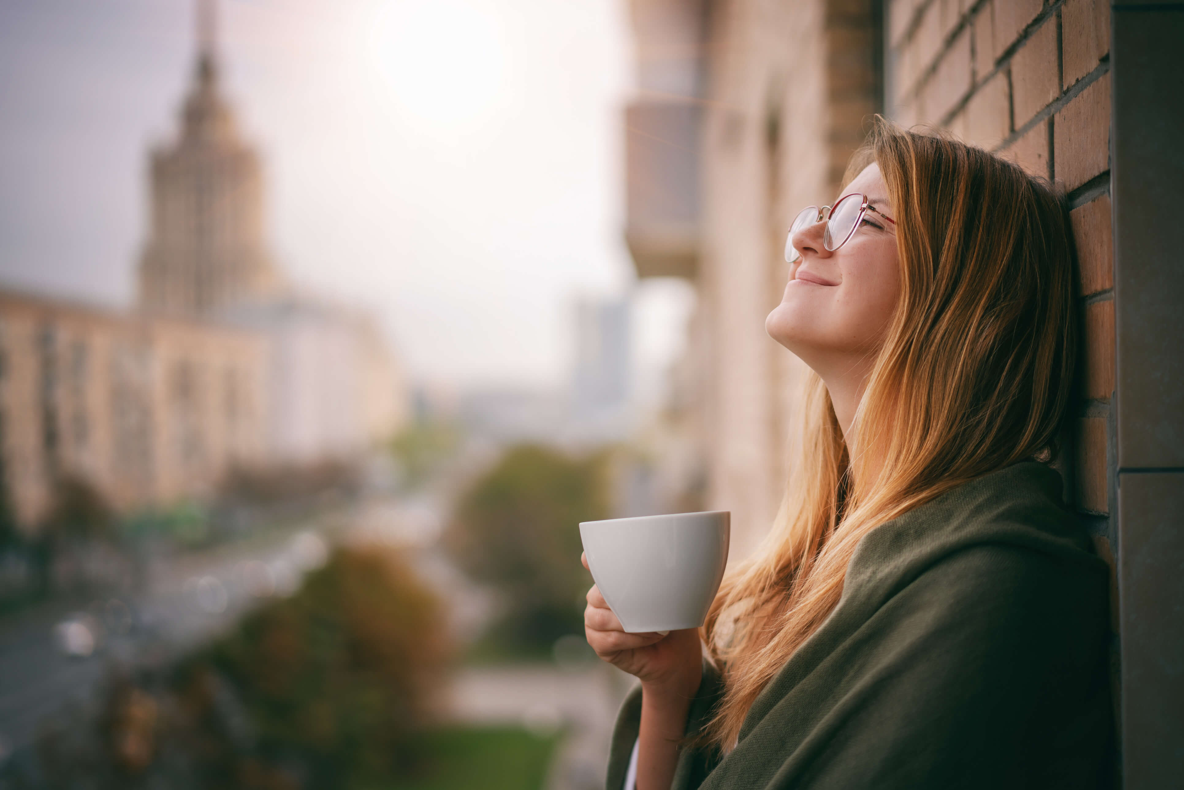 Vrouw geniet van een rustig koffiemoment op een hotelbalkon in de stad